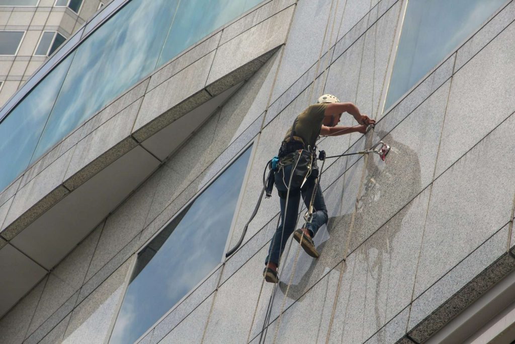 Person bei Aussenreinigung Gebäude mit Sicherungsausrüstung